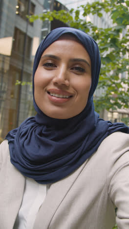 Vertical-Video-POV-Shot-Of-Muslim-Businesswoman-Making-Video-Call-On-Mobile-Phone-Outdoors-In-City